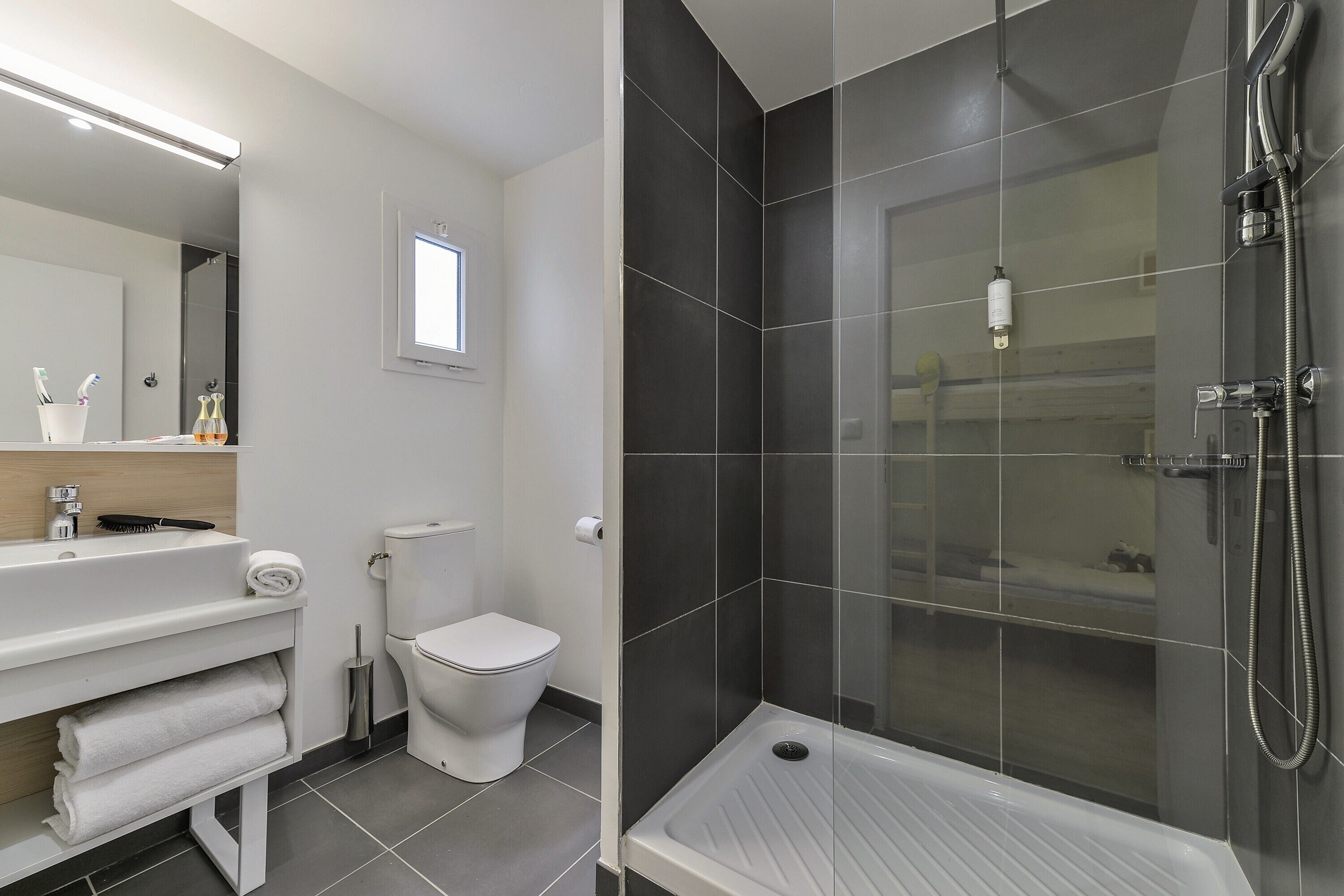 Een moderne badkamer met een wit wastafelmeubel, toilet en een douchecabine.