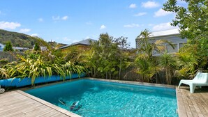 A rectangular swimming pool with clear blue water, surrounded by a wooden deck and various tropical plants. - Seaview Apollo Escape (Apollo Bay)
