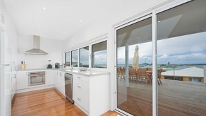 A modern kitchen with a large sliding glass door leading to an outdoor deck. - Seaview Apollo Escape (Apollo Bay)