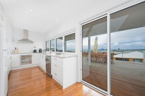 A modern kitchen with a large sliding glass door leading to an outdoor deck. - Seaview Apollo Escape (Apollo Bay)