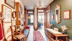 A hallway with a wooden bench, chairs, a red rug, and framed pictures on the walls. - Timeless Elegance | Walk to Capitol & Attractions | Historic Luxury (Springfield)