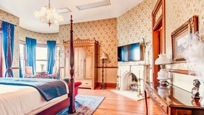 A bedroom with a four-poster bed, wooden wardrobe, television, fireplace, and a mirror. - Timeless Elegance | Walk to Capitol & Attractions | Historic Luxury (Springfield)