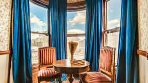 A room with a round table, two striped chairs, and a vase of dried flowers. - Timeless Elegance | Walk to Capitol & Attractions | Historic Luxury (Springfield)