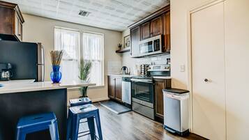 Une cuisine moderne avec des meubles en bois, des appareils en acier inoxydable et un vase bleu posé sur le plan de travail.