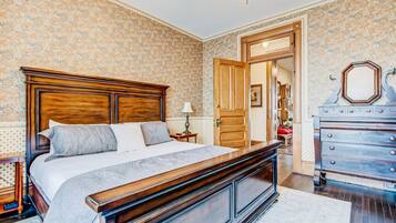 A bedroom with a wooden bed, a dresser, and a patterned wallpaper.