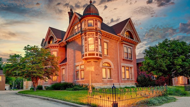 A large, two-story brick house with a prominent corner turret and multiple windows.