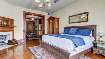 Ein Schlafzimmer mit einem großen Bett, einem Holz-Kopfteil, einer Chandelier, einem Kamin und einem Spiegel an der Wand.