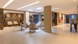 A modern lobby with a seating area, a reception desk, and a staircase. - Hotel Annamar Premium (João Pessoa)