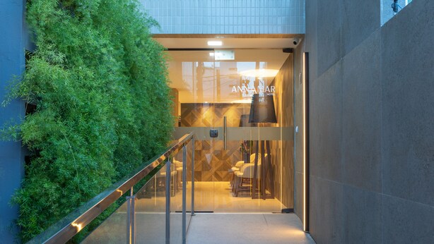 A modern hotel entrance with a glass door, a reception desk, and a seating area visible through the glass. - Hotel Annamar Premium (João Pessoa)