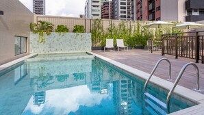 A rooftop swimming pool with a tiled deck, two lounge chairs, and a pergola with umbrellas. - Hotel Annamar Premium (João Pessoa)