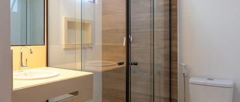 A modern bathroom with a glass-enclosed shower, a white sink, and a toilet.