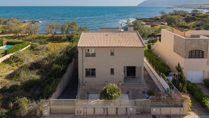 Une propriété située sur la côte, avec un bâtiment doté d’un toit en tuiles, une piscine et une vue sur la mer.