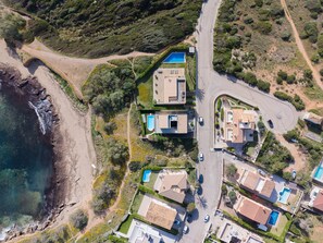 Vista aérea de uma área residencial costeira com casas, uma estrada e uma praia.