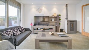 Un salon moderne comprenant un canapé, une table basse, un téléviseur à écran plat et un meuble de rangement intégré pour les appareils multimédias.
