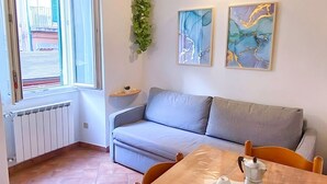 Un salon chaleureux avec une table en bois mise pour le thé, un canapé gris et deux tableaux abstraits accrochés au mur.