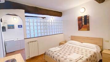 Ein Schlafzimmer mit einem Bett, einem Schreibtisch, einem Heizkörper und einem Fenster mit Blick.