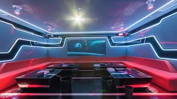 A futuristic lounge area with a curved seating arrangement, a large screen, and ambient lighting.