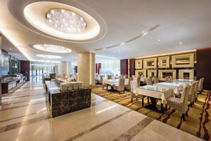 A spacious hotel lobby with a long reception desk, a dining area with round tables, and a bar. - Minzhong Grand Hotel (Youxi)