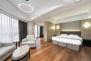 A modern hotel room with a large bed, a sofa, a small table, and a large window with curtains. - Minzhong Grand Hotel (Youxi)