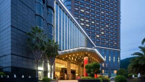Un hotel moderno con un ingresso curvo, ampie finestre e una facciata luminosa.