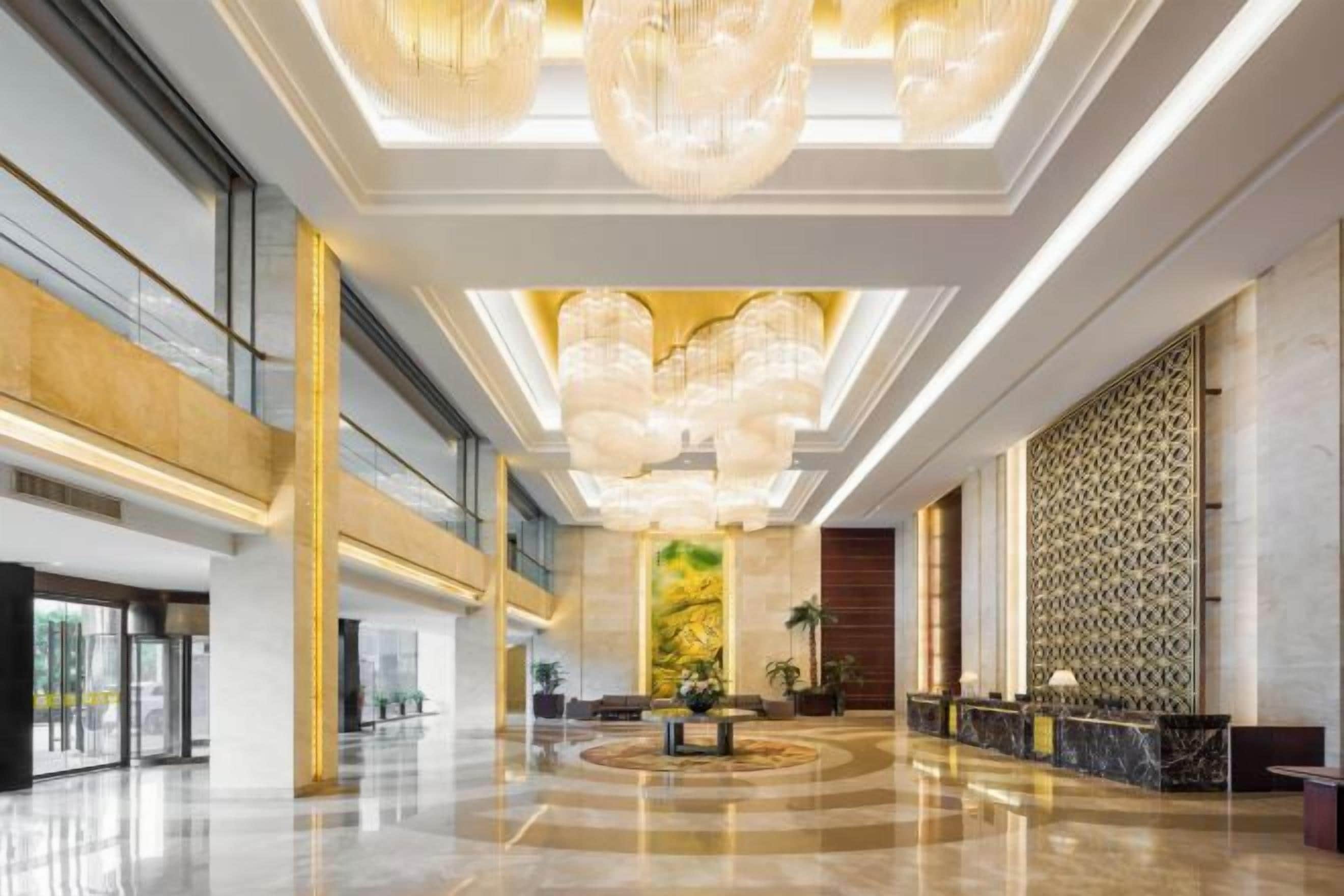 A spacious lobby with a high ceiling, large chandeliers, and a reception desk.