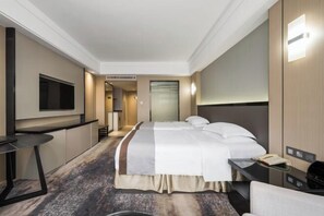 Een hotelkamer met een bed, een bureau, een televisie en een badkamer.
