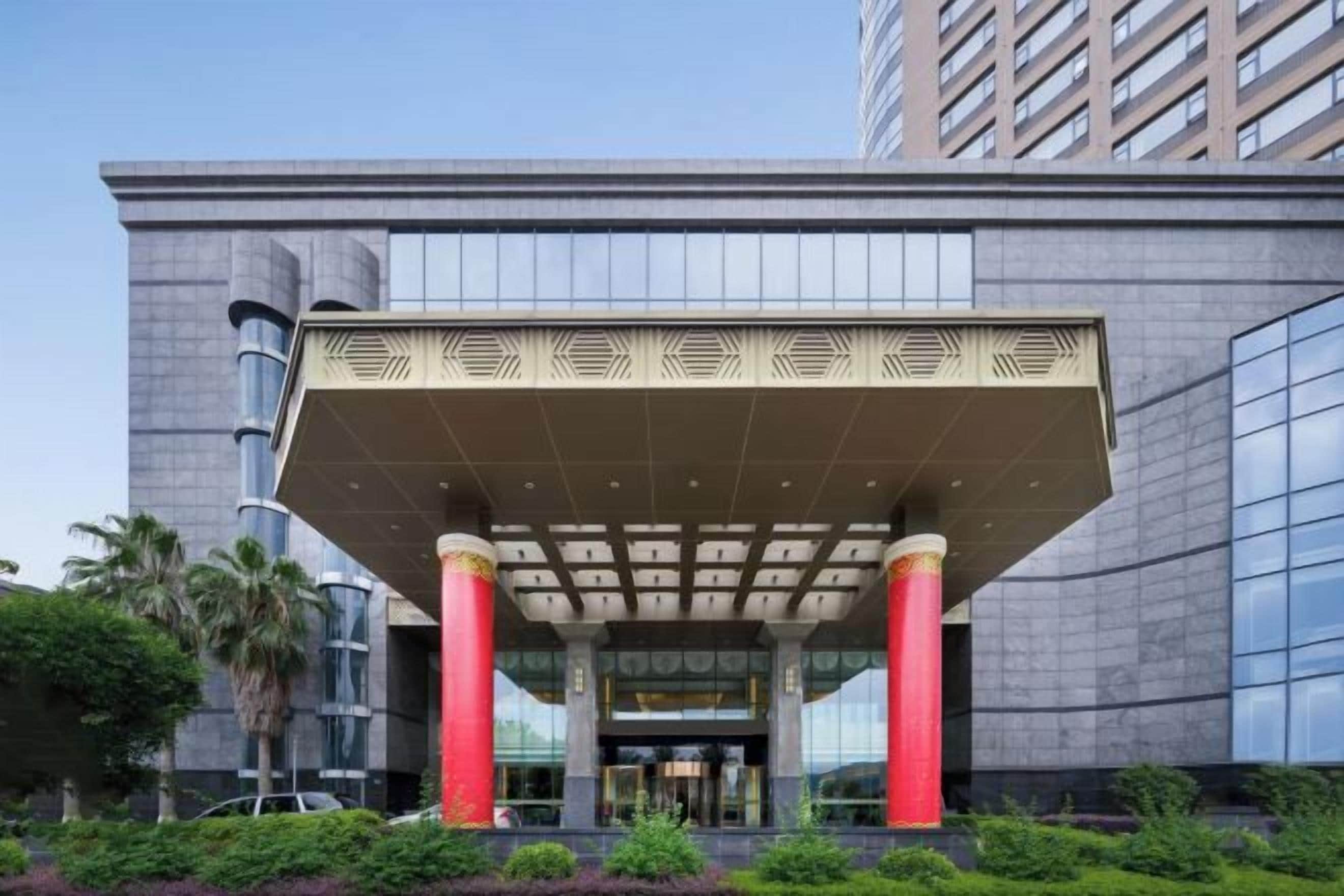 A modern building with a prominent entrance featuring a large overhang supported by columns.