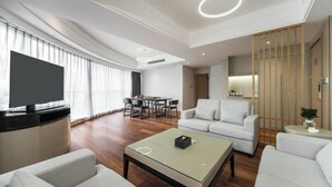 Un soggiorno moderno con una TV a schermo piatto, un'area pranzo e una cucina.