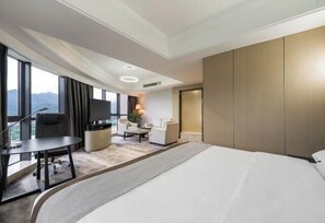 A modern hotel room with a large bed, a desk with a chair, a sofa, and a TV. - Minzhong Grand Hotel (Youxi)