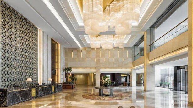 Un'ampia hall con pavimento in marmo, una reception e un grande lampadario.