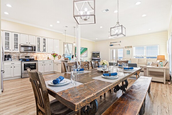 A spacious kitchen with white cabinets, a wooden dining table, and a large island. - Oceanfront Home · Pool · Arcade & Fire Pit (Gulf Shores)