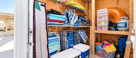 A storage room with shelves, bins, and a cooler.