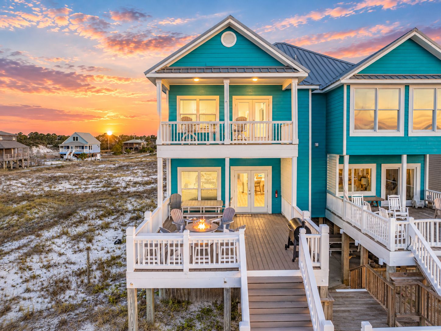 Ein zweistöckiges Strandhaus mit Balkon, Terrasse und Sitzbereich im Freien.