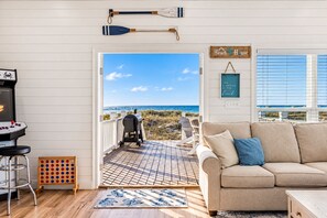 Et strandhusinteriør med havudsigt, grill, strandstol og hyggeligt opholdsområde.