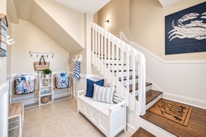 A staircase with white railings leading to a landing area with a bench and a basket. - Oceanfront Home · Pool · Arcade & Fire Pit (Gulf Shores)