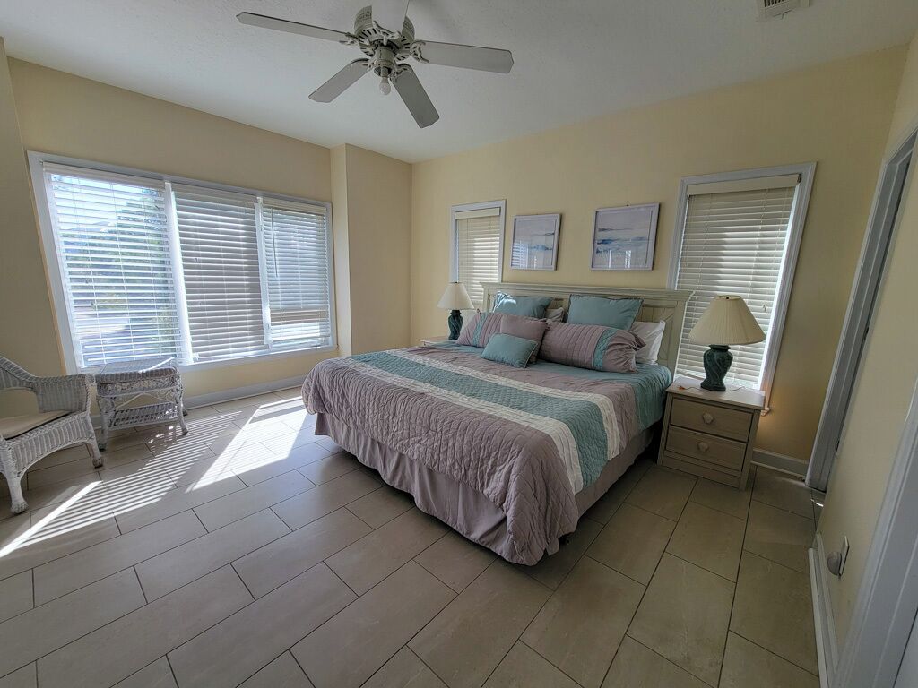 A bedroom with a bed, a chair, a nightstand, and a ceiling fan.