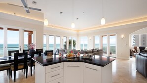 A spacious kitchen with a central island, large windows, and a view of the ocean.