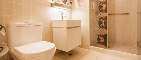 Une salle de bain équipée de toilettes, d’un lavabo et d’une douche avec une porte en verre.