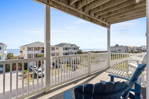 A covered balcony with a view of the ocean and neighboring houses. - CottageVacations4u "Shore Thing"- ocean views-direct beach access-pool club<br>Golf cart friendly (Ocean Isle Beach)