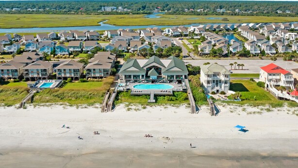 A coastal residential area with houses, a large swimming pool, and a beach. - CottageVacations4u "Shore Thing"- ocean views-direct beach access-pool club<br>Golf cart friendly (Ocean Isle Beach)