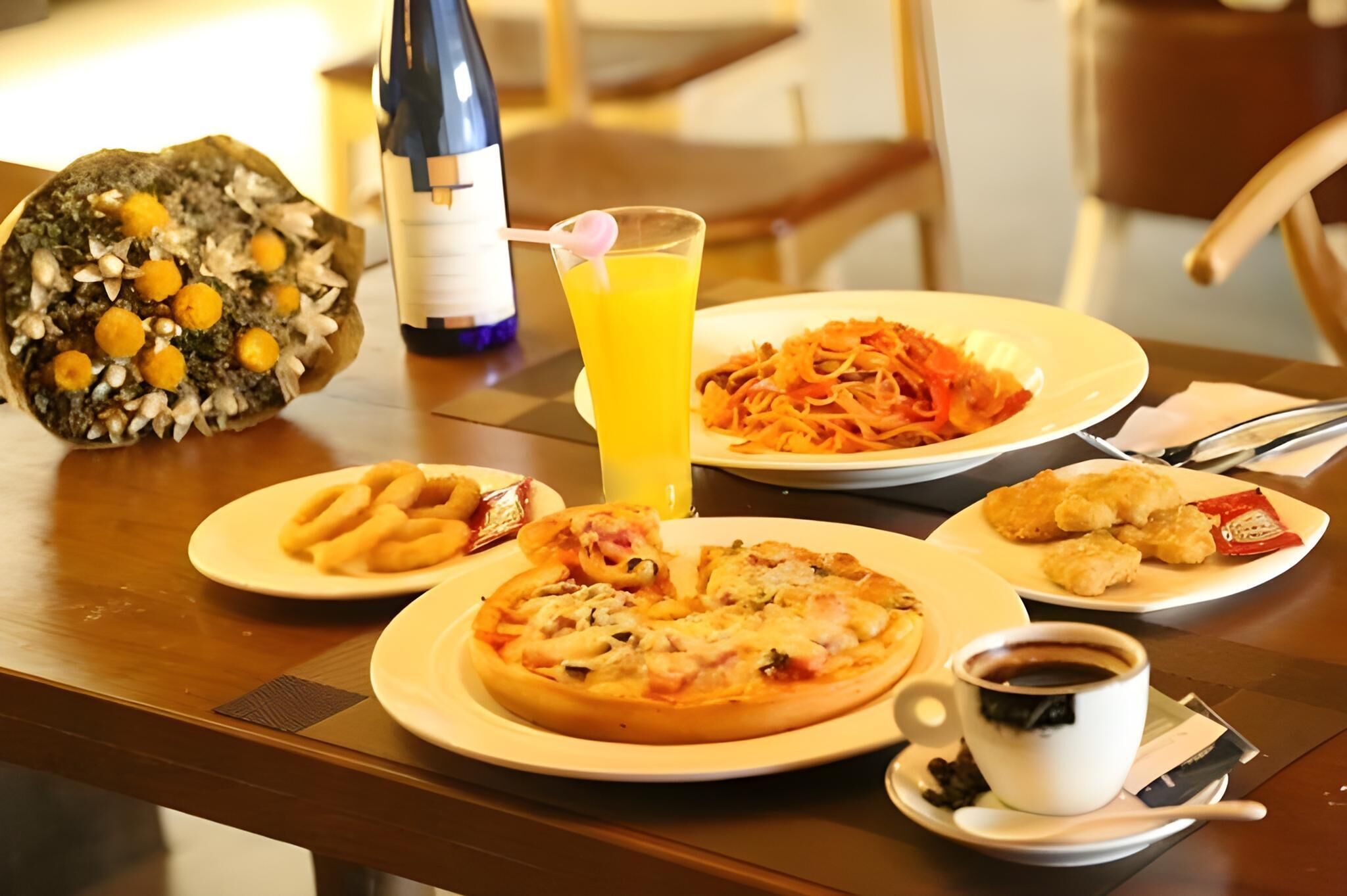 A breakfast table with plates of food, a bottle of water, a glass of orange juice, and a cup of coffee.