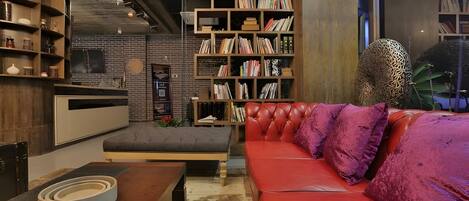 Un soggiorno moderno con un divano in pelle rossa, una libreria in legno e una parete in mattoni.