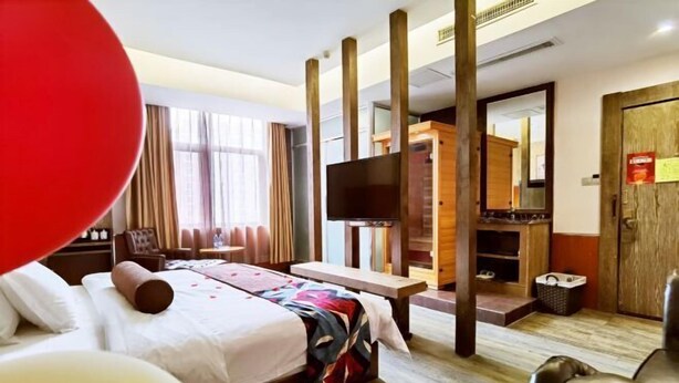 Una habitación de hotel con cama, escritorio, televisor y armario.
