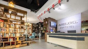 Un acogedor interior de cafetería con estanterías de madera, un mostrador de recepción y un letrero en la pared que dice "James Joyce Coffee".
