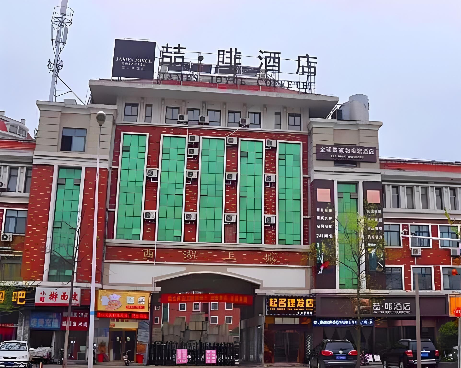 Un hôtel à la façade rouge, doté de nombreuses fenêtres et d’une enseigne avec des caractères chinois.