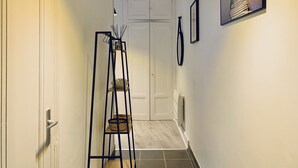 A hallway with a white door at the end, a black metal ladder, and a framed picture on the wall.