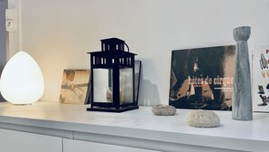 A modern interior with a white countertop displaying a black lantern, a framed photograph, a book titled 'betes de cirque', and a decorative stone.