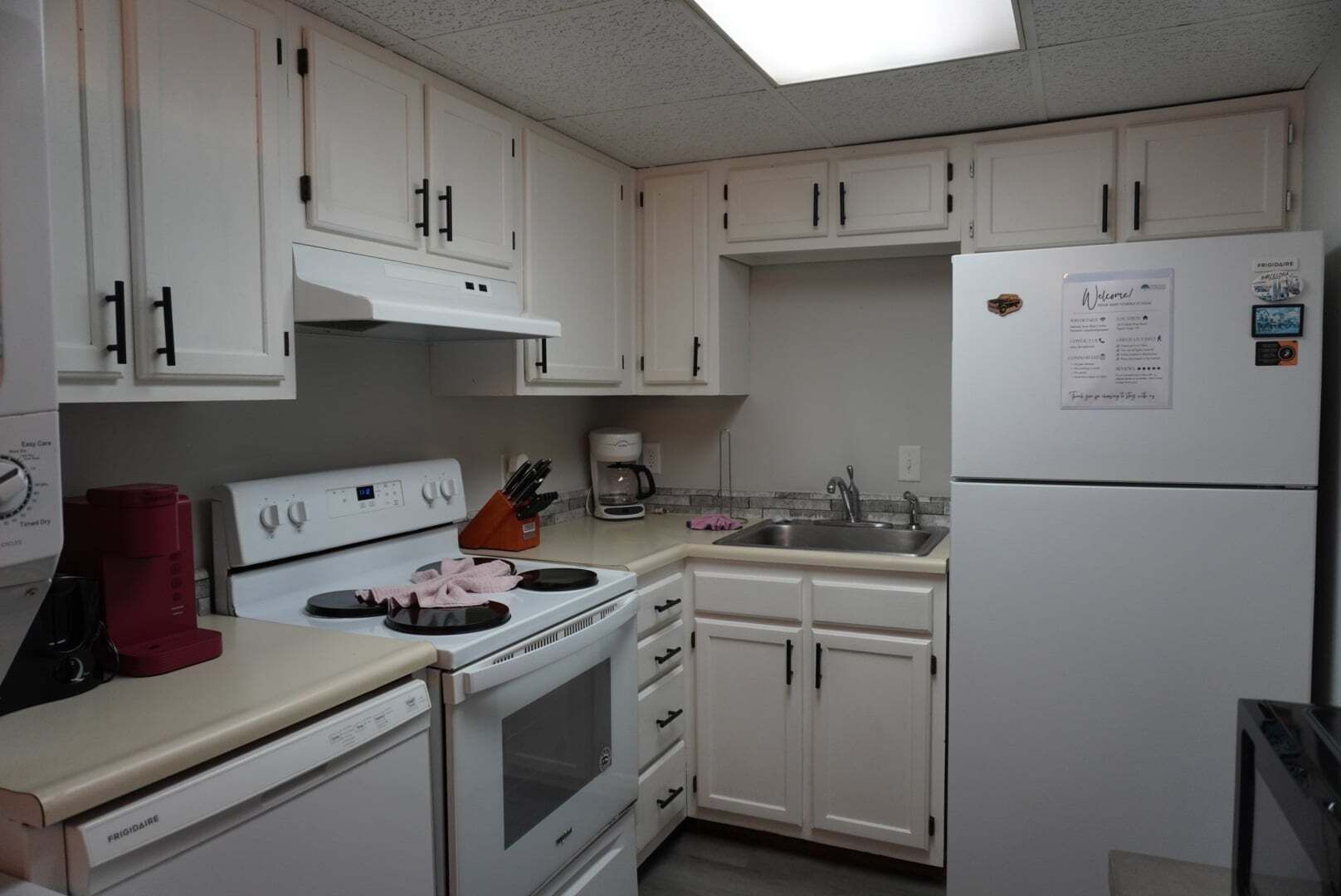 A kitchen with white cabinets, a stove, a sink, and a refrigerator.