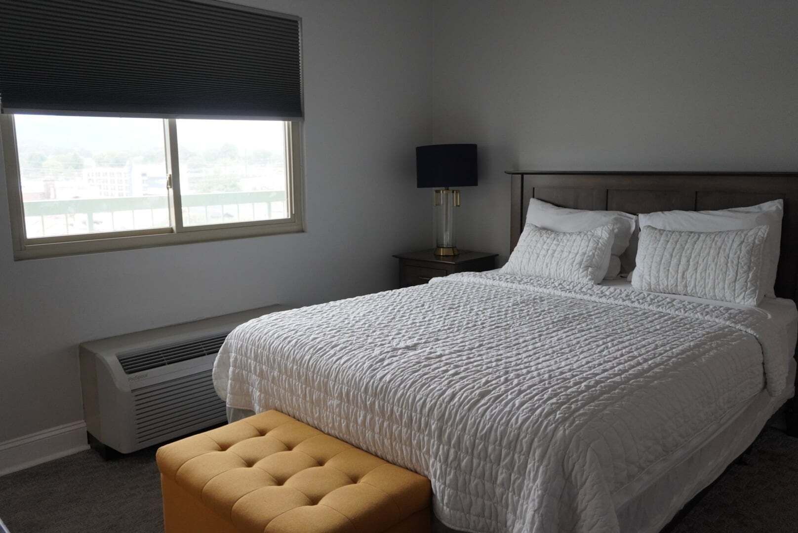 Un dormitorio con una cama grande, una ventana con persianas, una lámpara de noche y un calentador.