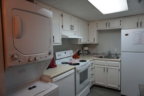 A compact kitchen with white cabinets, a stove, an oven, a microwave, and a refrigerator. - Smoky Mountains 603 2BD with Private Balcony and Jacuzzi Tub by RedAwning (Pigeon Forge)